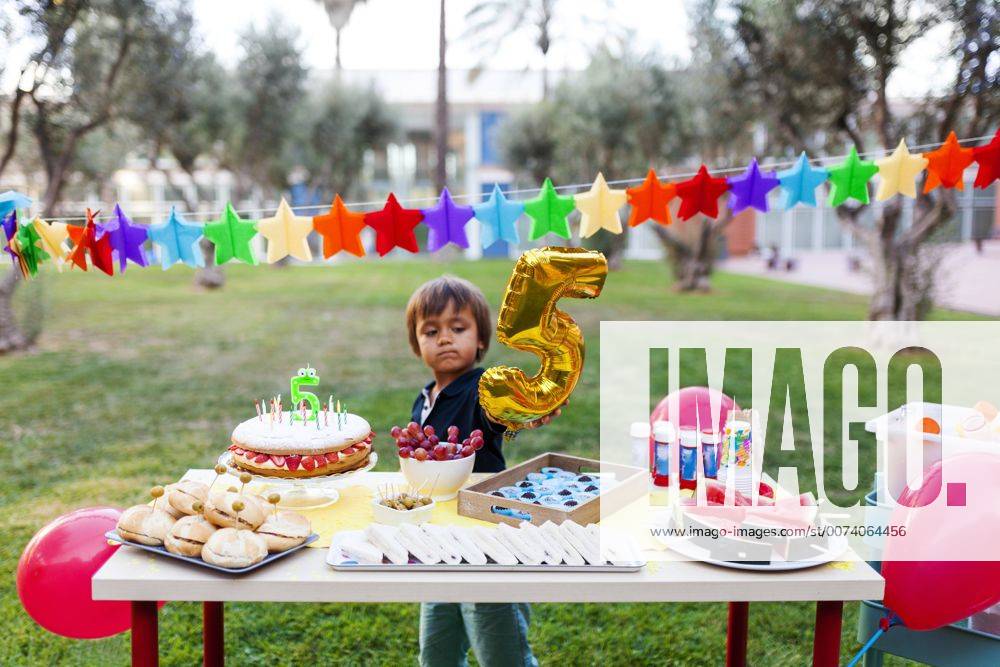 Little boy with golden balloon behind laid birthday table model released Symbolfoto VABF00771