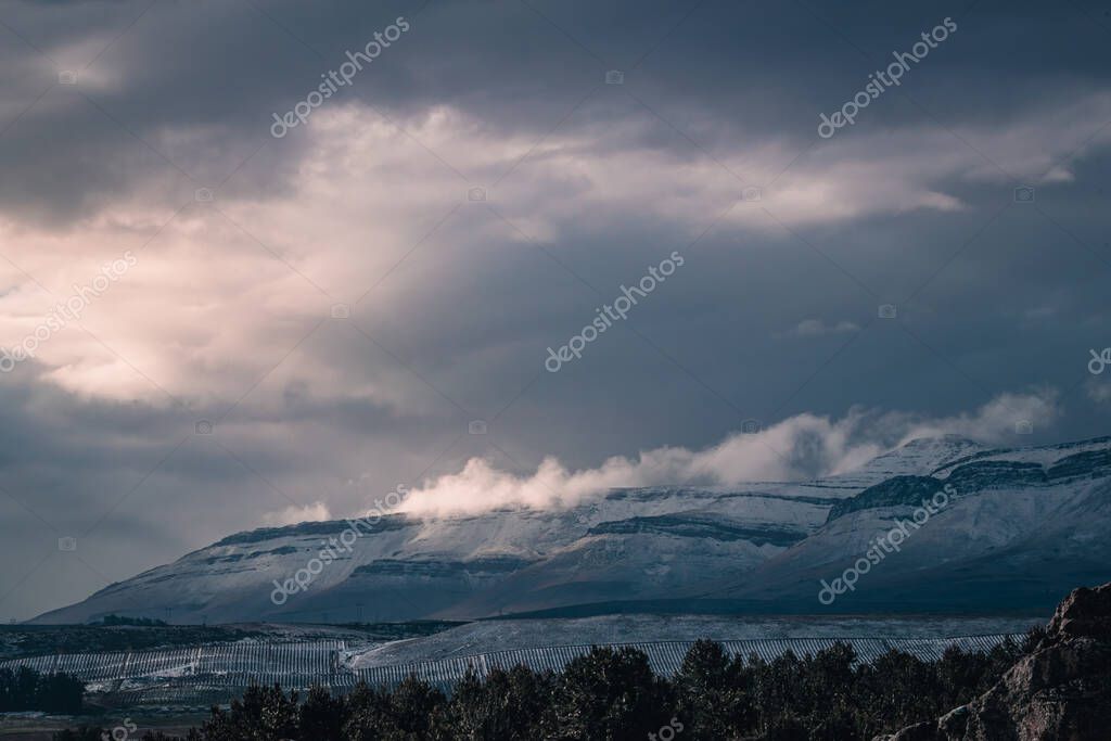 A beautiful landscape view of trees under snow cliffs against a gray sky in Matroosberg, South Africa