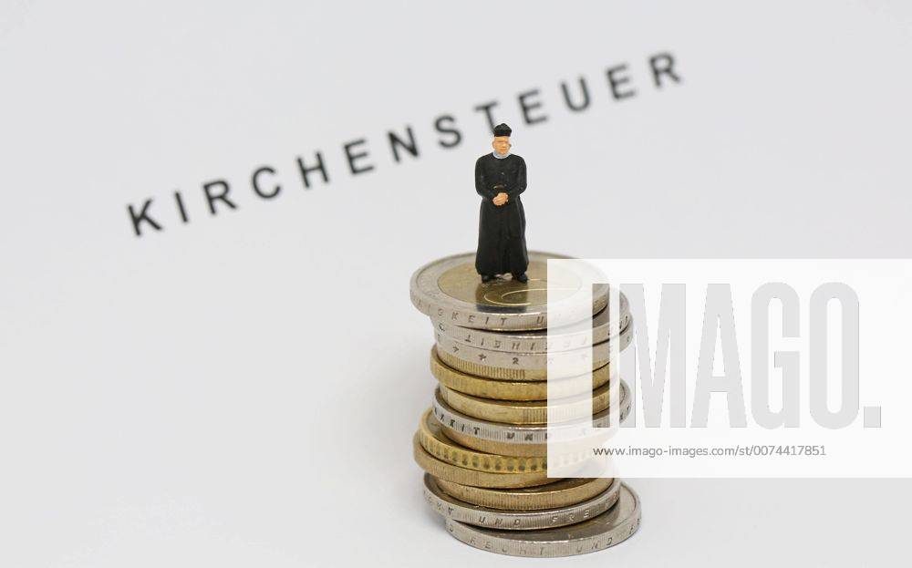 Nuernberg Symbolfoto, Themenbild Kirchensteuer. Geistlicher mit Soutane steht auf Euro Muenzen. Im Hintergrund Schriftzug Kirchensteuer.
