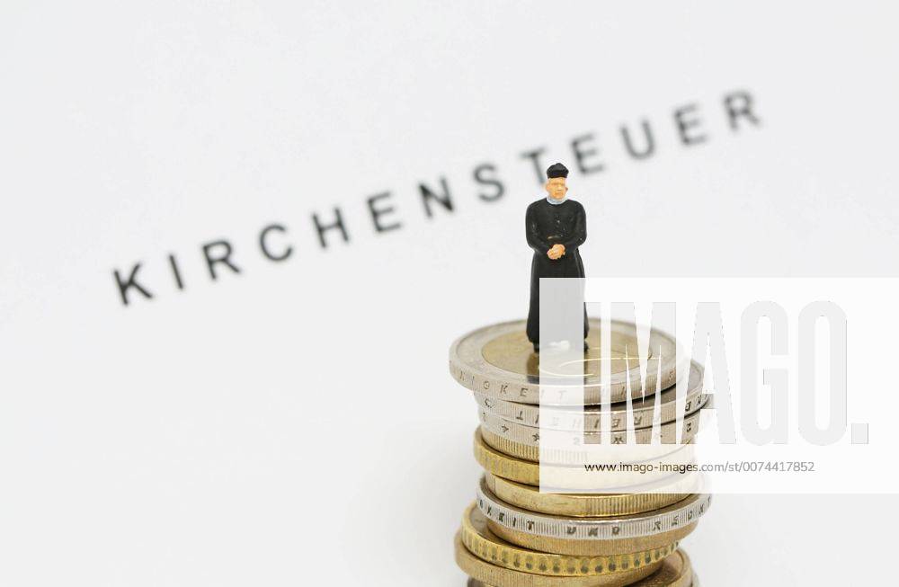 Nuernberg Symbolfoto, Themenbild Kirchensteuer. Geistlicher mit Soutane steht auf Euro Muenzen. Im Hintergrund Schriftzug Kirchensteuer.