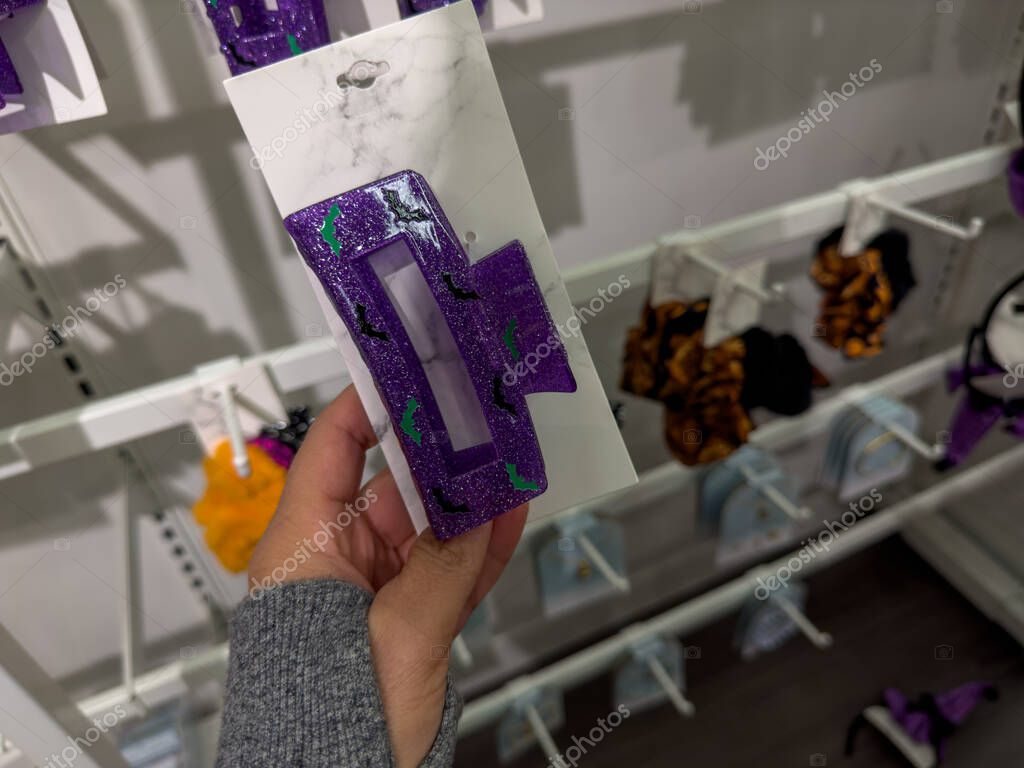 Plymouth, Minnesota - October 8, 2022: Hand holds up a purple Halloween claw clip hair accessory while shopping at a Target store