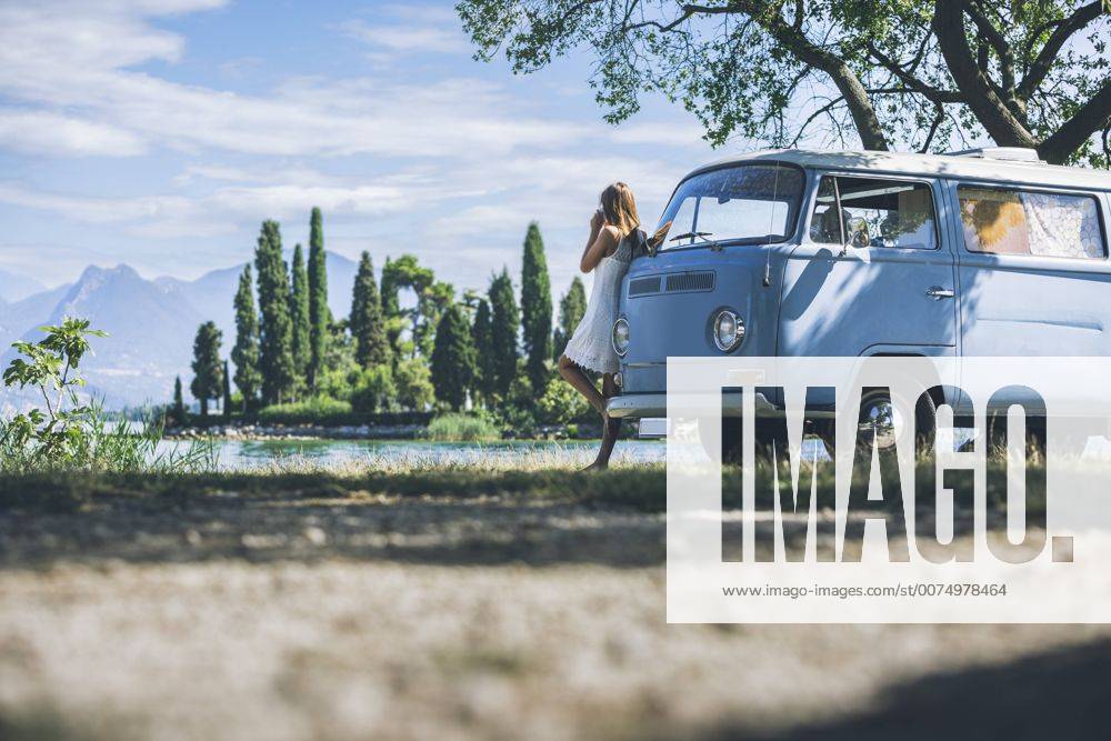 Italy, Lake Garda, young woman drinking coffee at camping bus model released Symbolfoto SBOF00260