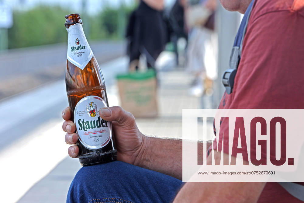Verschwendete Zeit Ein Mann hält sein Feierabendbier in der Hand und wartet auf ein Zug der nicht kommt