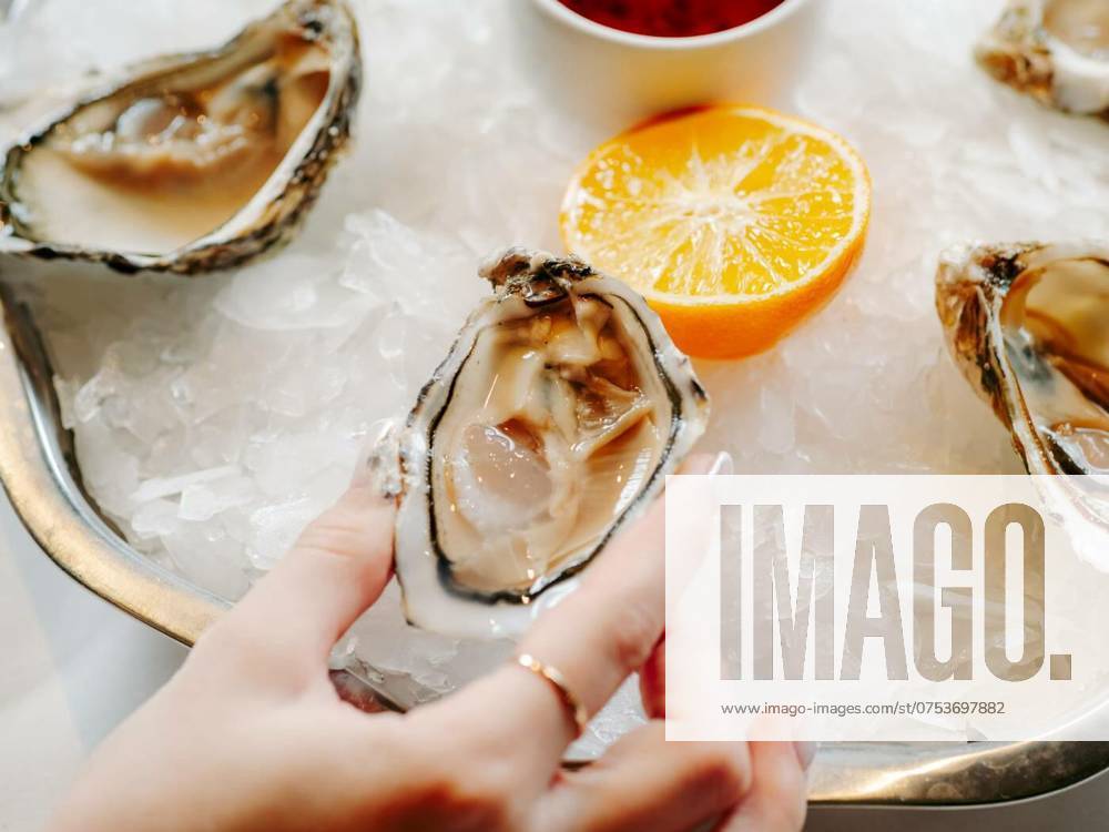 Woman having oysters at table, Woman having oysters at table. Fresh oysters on large plate with ice and lemon. Healthy food, gourmet food, restaurant food. Mediterranean cuisine, girl eats, oysters on ice, Woman having oysters at table. Fresh oysters on large plate with ice and lemon. Healthy food, gourmet food, restaurant food. Mediterranean cuisine, girl eats, oysters on ice, 25.02.2024,