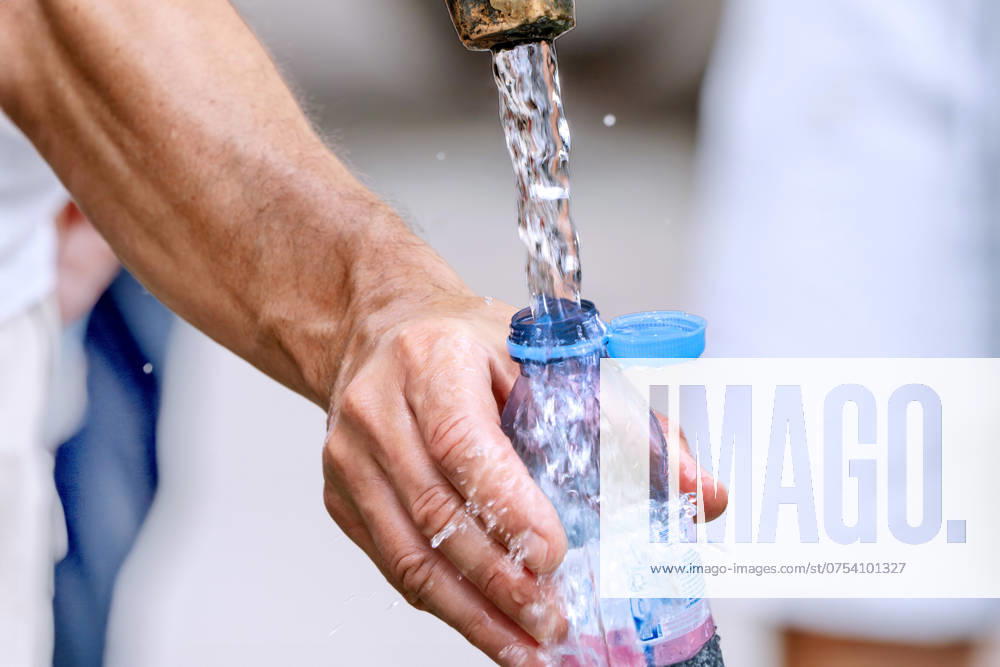 IMAGO Creative, Jahreszeit Sommer, Hitze Mann füllt seine Wasserflasche mit frischem Trinkwasser, Brunnen am Marienplatz, Hochsommer, München, August 2024 Deutschland, München, August 2024, ein Mann füllt seine Wasserflasche mit frischem Trinkwasser am Brunnen auf, bei der Sommerhitze ist Trinken besonders wichtig, Brunnenwasser bringt Abkühlung an einem warmen Sommertag, Temperaturen über 30 Grad, Rekordhitze, Flasche mit neuem Verschluß, Plastikdeckel fest mit der Flasche verbunden, Sommerwetter, Hochsommer, Sommer, Bayern,
