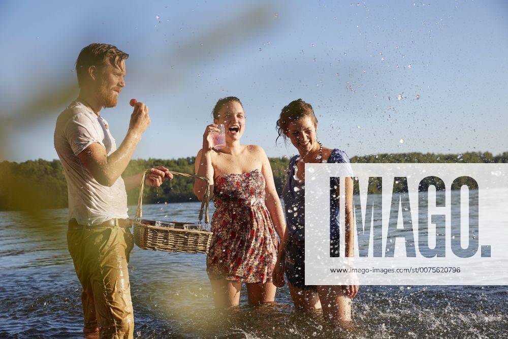 Playful friends splashing in a lake taking a drink model released Symbolfoto FMKF03282