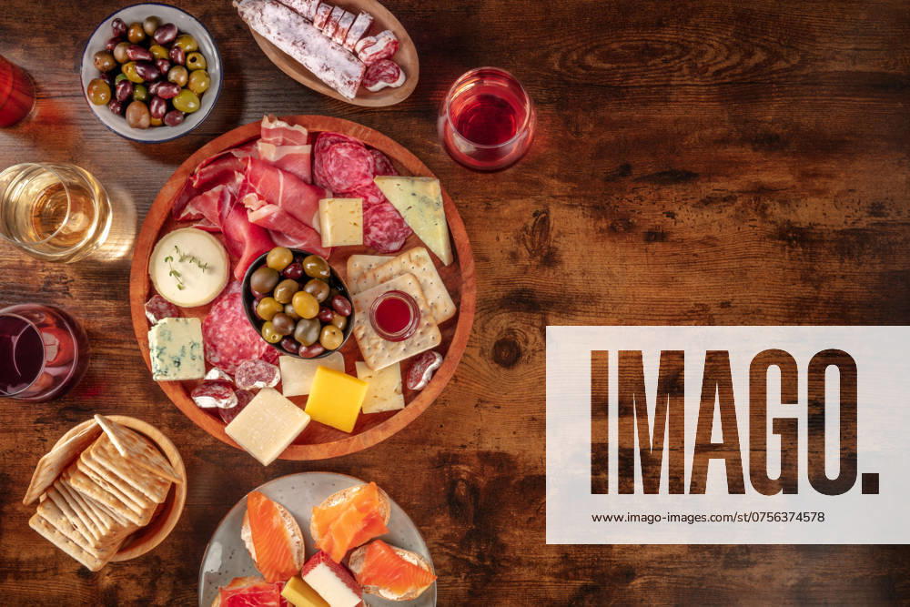 IMAGO Creative, Food, Tapas Charcuterie und Käseplatte mit Wein, Overhead Flat Lay Aufnahme auf rustikalem Hintergrund mit Platz für Text. Italienische Antipasti oder spanische Tapas, Aufnahme von oben mit Oliven und Lachssandwiches Charcuterie and cheese board with wine, overhead flat lay shot on a rustic background with a place for text. Italian antipasti or Spanish tapas, shot from above with olives and salmon sandwiches