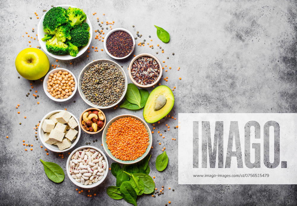 Vielfalt an nährstoffreichen Lebensmitteln für Veganer mit Kopierfläche: Bohnen, Linsen, Quinoa, Tofu, Gemüse, Nüsse, Kichererbsen, Reis, Avocado, Obst, Steinhintergrund, Draufsicht. Gesunde vegetarische Ernährung Variety of nutrient-rich food for vegans with copy space: beans, lentils, quinoa, tofu, vegetables, nuts, chickpeas, rice, avocado, fruit, stone background, top view. Healthy vegetarian nutrition