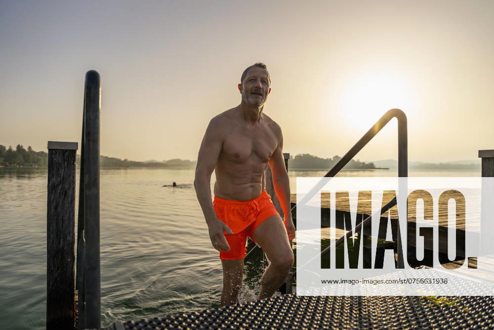 Shirtless senior man disembarking from lake at sunrise model released, Symbolfoto, DIGF21635