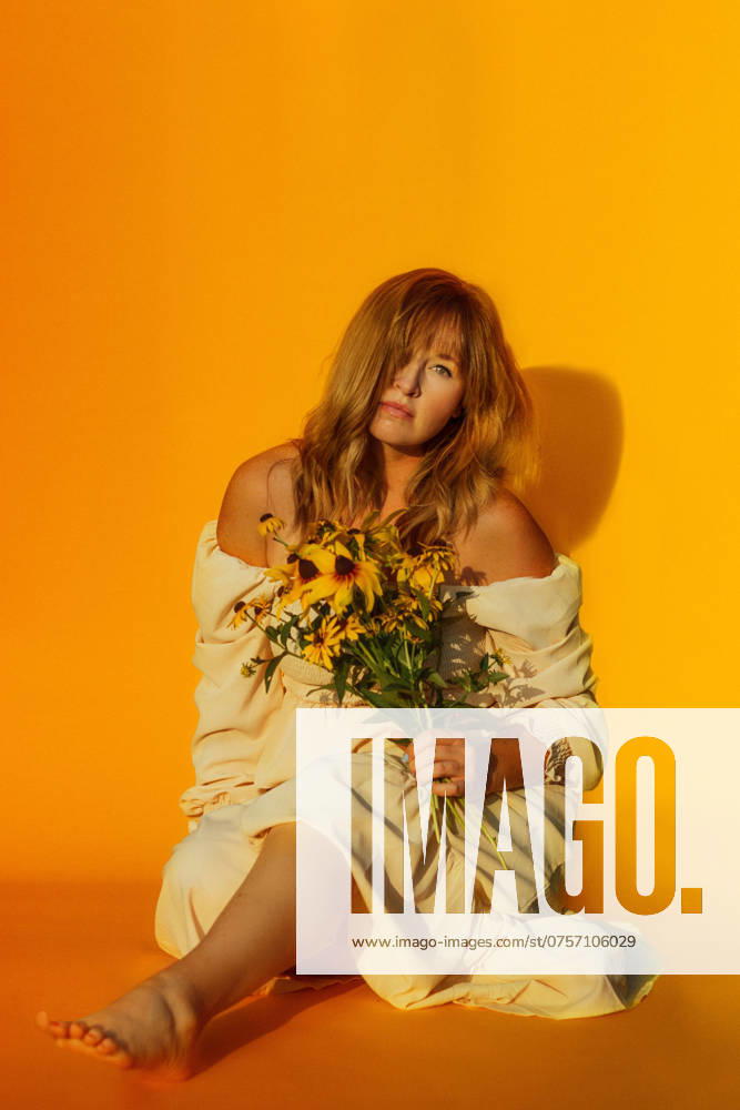 Woman holding yellow flowers in front of a yellow backdrop Tulsa, Oklahoma, United States R_KRRY240821-1521128-01 ,model released, Symbolfoto