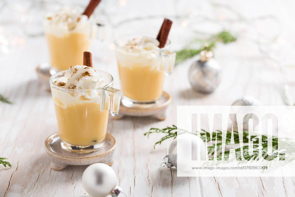 Eierlikör mit Zimt und Muskatnuss für Weihnachten und Winterferien. Mit weihnachtlichen Dekorationen auf hölzernem Hintergrund Eggnog with cinnamon and nutmeg for Christmas and winter holidays. With Xmas decorations on wooden background