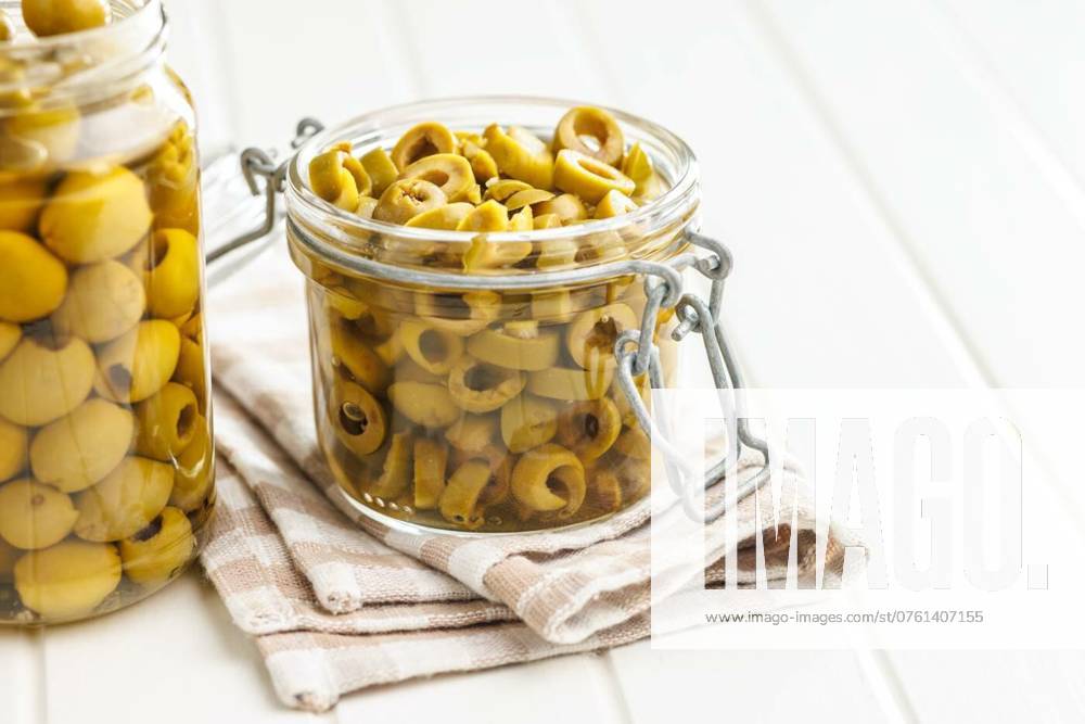 Sliced pickled green olives in brine in jar on white table., Sliced pickled green olives in brine in jar on a white table., Sliced pickled green olives in brine in jar on a white table., 07.08.2024,