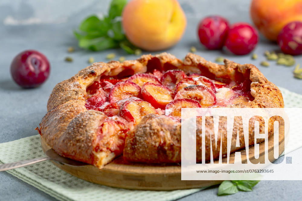 Fruit open pie (galette). Sliced delicious homemade open pie (galette) with red cherry plum, peaches and fragrant cardamom. Selective focus.