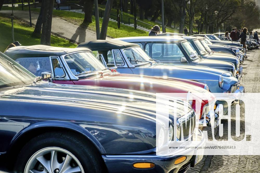 Lissabon, Portugal, 20. Januar 2024: Eine Reihe glänzender Oldtimer der Marken Jaguar, MG, Triumph und Mini und andere parken auf einer kopfsteingepflasterten Auffahrt in der Nähe eines grünen Parks, Europa Lisbon, Portugal, Jan 20, 2024: A row of shiny vintage cars of Jaguar, MG, Triumph and Mini brands and others parked on cobblestone driveway near green park, Europe