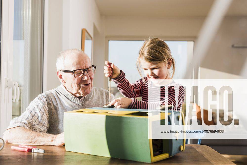 Grandfather and granddaughter assembling toy bus model released Symbolfoto property released UUF09549