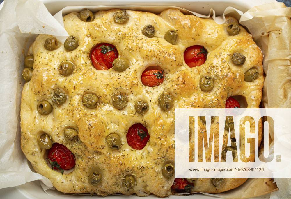 Overhead von traditionellen italienischen hausgemachten Fladenbrot Focaccia mit grünen Oliven, Olivenöl, Kirschtomaten und Rosmarin in Backblech auf rustikalen dunkelblauen Beton Hintergrund, Lebensmittel Fotografie Overhead of Traditional Italian Homemade Flat Bread Focaccia with Green Olives, Olive Oil, Cherry Tomatoes and Rosemary in Baking Tray on Rustic Dark Blue Concrete Background, food photography, food photography