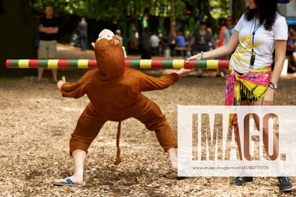 Summer, vacation and man in game of limbo, balance and playing at a music festival, event and challenge. Fun, people and outdoor in woods, forest or person in social activity at party in monkey suit. model released property released