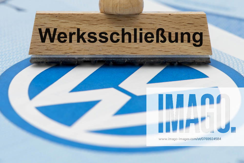 VW-Krise mit Gefahr der Werksschließung Ein Holzstempel ist beschriftet mit dem Aufdruck: Werksschließung, über einer VW-Aktie mit Logo - Symbolbild