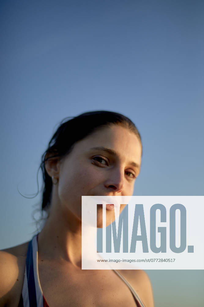 Portrait of a young woman with a serene expression against a clear blue sky at dusk. bola03240