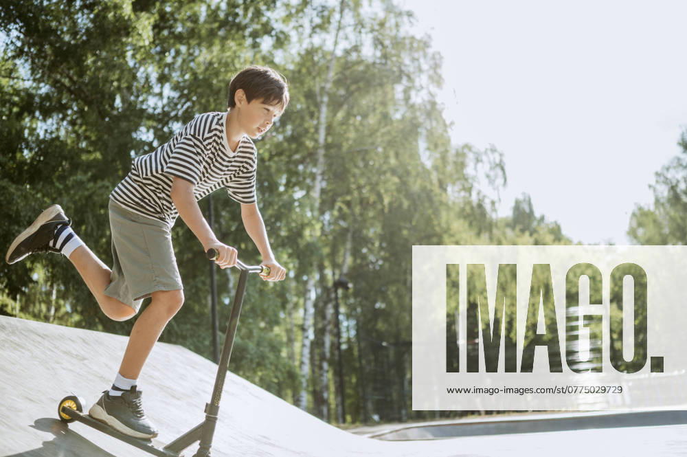 Pre-adolescent boy riding push scooter on sunny day model released, Symbolfoto, ANAF03914