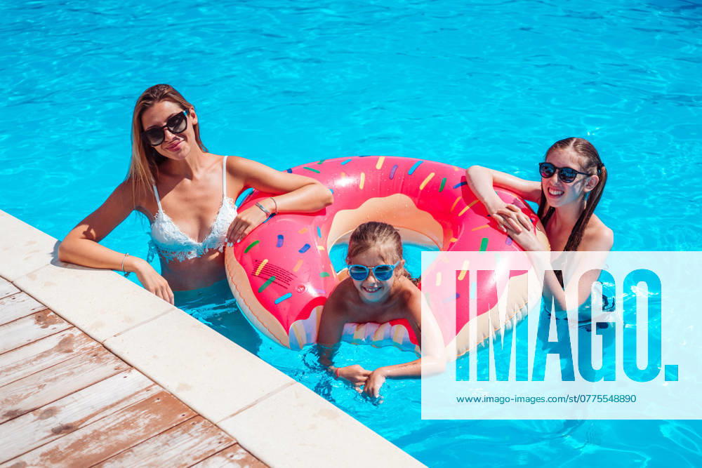 Mother with two daughters in the pool Mom with two daughters in the pool posing at the camera ,model released, Symbolfoto