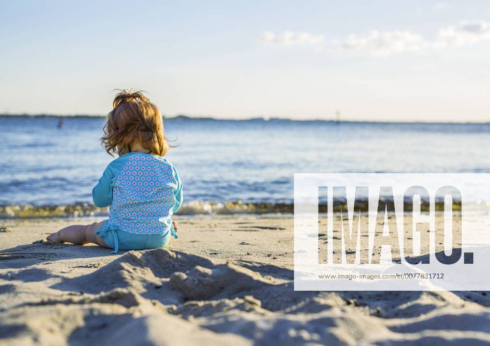 Kleinkind sitzt sehr nah am Meer (model-released)