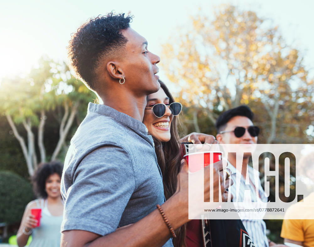 Drinks, party and a couple of friends outdoor to celebrate at festival, concert or summer social event. Diversity young men and women crowd while happy, hug and drinking alcohol while listening. model released property released