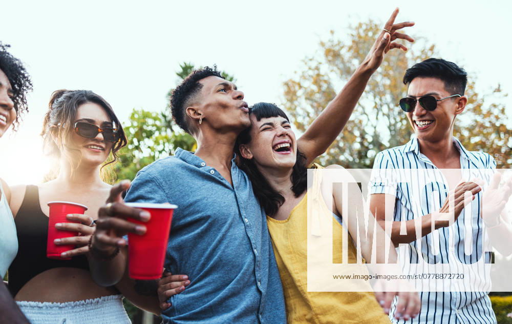 Drinks, party and a couple of friends dancing outdoor to celebrate at festival, concert or social event. Diversity young men and women people together in summer, happy and drinking alcohol in crowd. model released property released