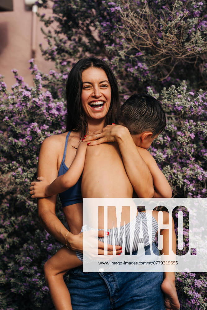 IMAGO Creative, Sommer, Sommertage im Garten Laughing mother embraces young son in front of purple flowers Joshua Tree, California, United States CR_FKNH241101B-1575533-01 ,model released, Symbolfoto
