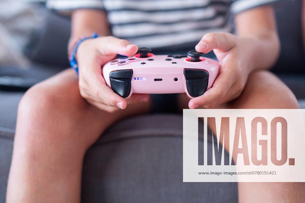 IMAGO Creative, Lifestyle, Gaming Close up of a child s hands holding a pink game controller focused on playing a video game, showcasing modern childhood interaction with technology Model Released HodeiUnzueta_ID24807_718907_019