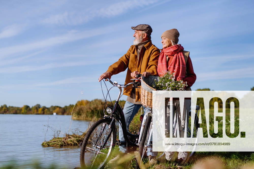 Lovely elderly couple on standing by lake with their bikes, enjoying a peaceful moment together. Lovely elderly couple on standing by lake with their bikes, enjoying peaceful moment together. model released