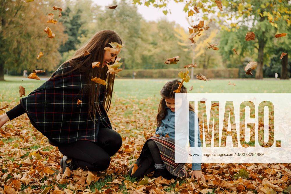 Young woman and little girl playing with autumn leaves on a meadow model released Symbolfoto CHAF01812