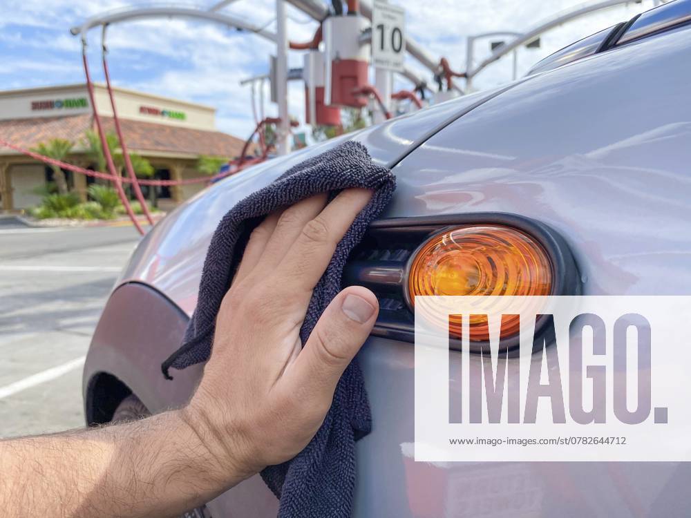 Männerhand beim Reinigen des Autos mit schwarzem Mikrofasertuch. Hand abwischen Oberfläche des Autos. Car Detailing und Autowäsche Konzept, San Diego, USA, 13. August 2020, Nordamerika Man s hand cleaning the car with black microfiber cloth. Hand wipe down surface of car. Car detailing and car wash concept, San Diego, USA, August 13th, 2020, North America