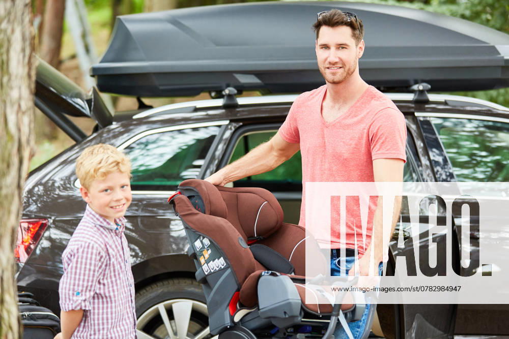 Vater und Sohn montieren gemeinsam einen Kindersitz im Auto vor der Reise ,model released, Symbolfoto
