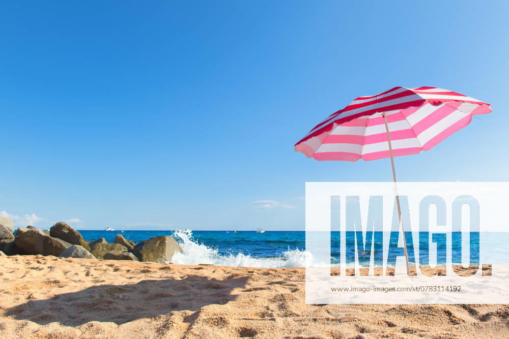 Beach with parasol Empty beach with waves, sea and striped pink parasol