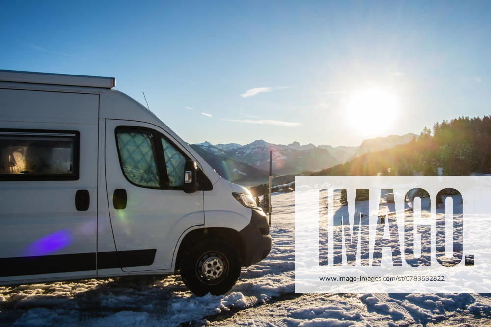 Ein Camper steht im Winter auf einem Parkplatz in den Alpen bei Sonnenaufgang im Schnee. Bödele, Vorarlberg, Österreich Winter in den österreichischen Alpen