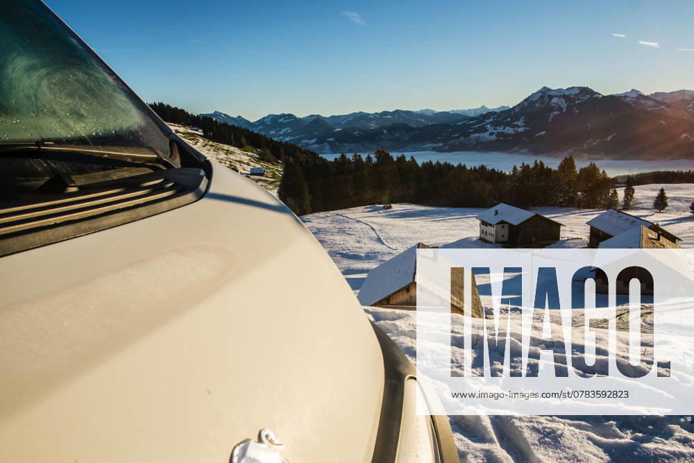 Ein Camper steht im Winter auf einem Parkplatz in den Alpen bei Sonnenaufgang im Schnee. Bödele, Vorarlberg, Österreich Winter in den österreichischen Alpen