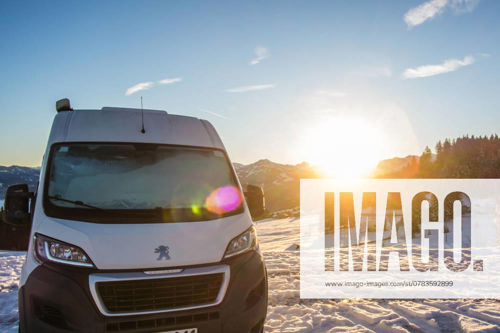 Ein Camper steht im Winter auf einem Parkplatz in den Alpen bei Sonnenaufgang im Schnee. Bödele, Vorarlberg, Österreich Winter in den österreichischen Alpen
