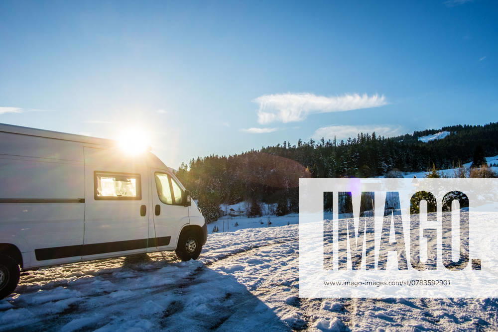 Ein Camper steht im Winter auf einem Parkplatz in den Alpen bei Sonnenaufgang im Schnee. Bödele, Vorarlberg, Österreich Winter in den österreichischen Alpen