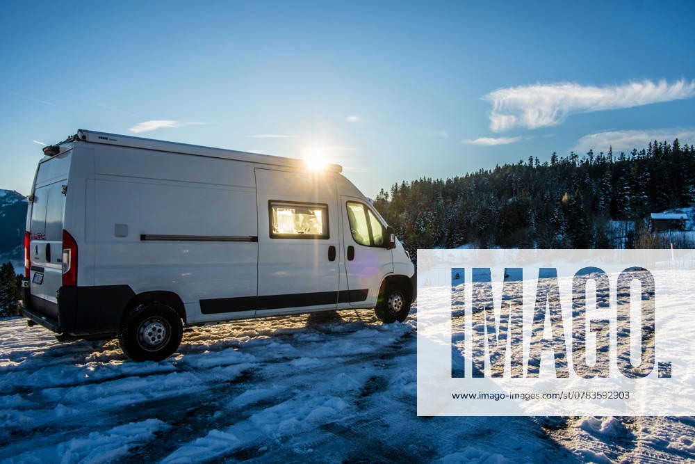 Ein Camper steht im Winter auf einem Parkplatz in den Alpen bei Sonnenaufgang im Schnee. Bödele, Vorarlberg, Österreich Winter in den österreichischen Alpen