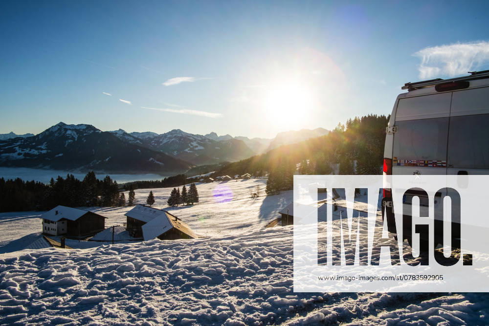 Ein Camper steht im Winter auf einem Parkplatz in den Alpen bei Sonnenaufgang im Schnee. Bödele, Vorarlberg, Österreich Winter in den österreichischen Alpen