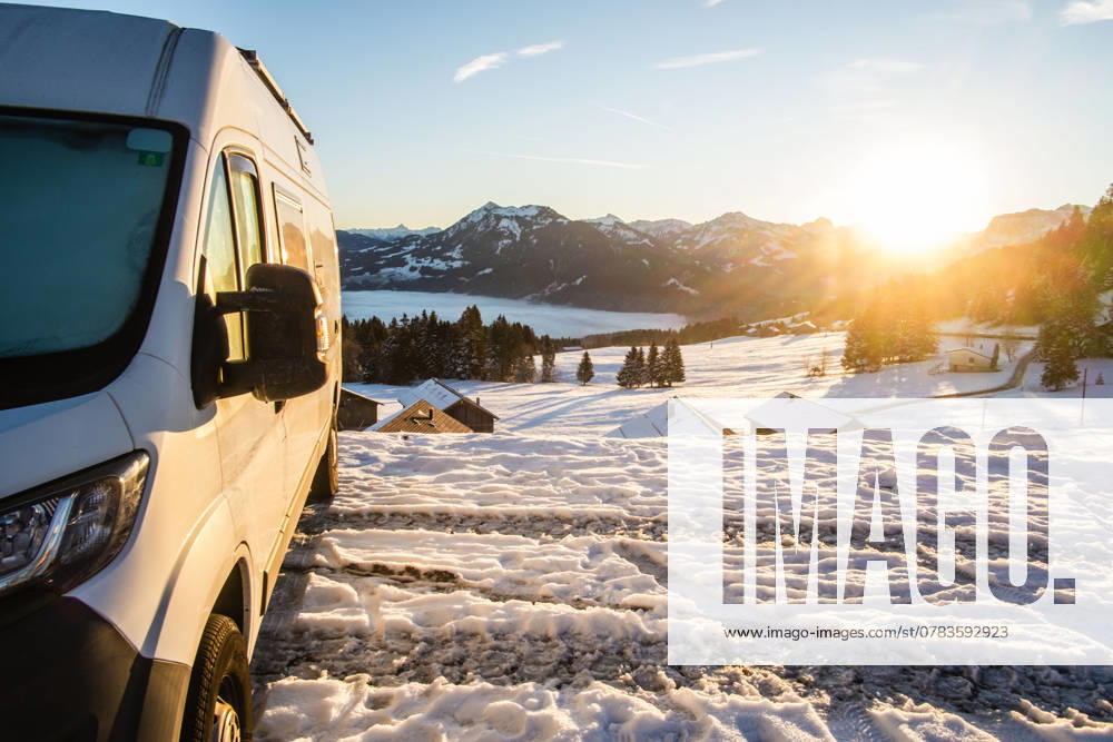Ein Camper steht im Winter auf einem Parkplatz in den Alpen bei Sonnenaufgang im Schnee. Bödele, Vorarlberg, Österreich Winter in den österreichischen Alpen