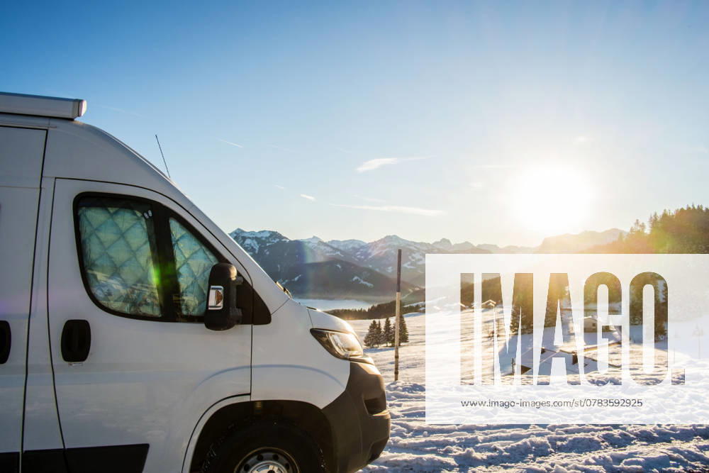 Ein Camper steht im Winter auf einem Parkplatz in den Alpen bei Sonnenaufgang im Schnee. Bödele, Vorarlberg, Österreich Winter in den österreichischen Alpen
