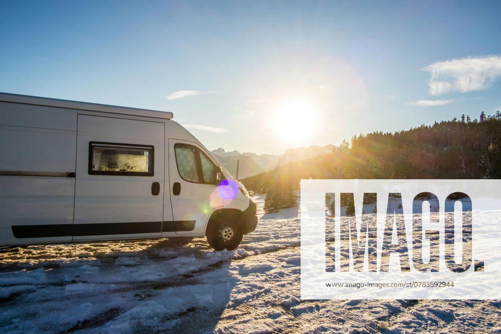 Ein Camper steht im Winter auf einem Parkplatz in den Alpen bei Sonnenaufgang im Schnee. Bödele, Vorarlberg, Österreich Winter in den österreichischen Alpen