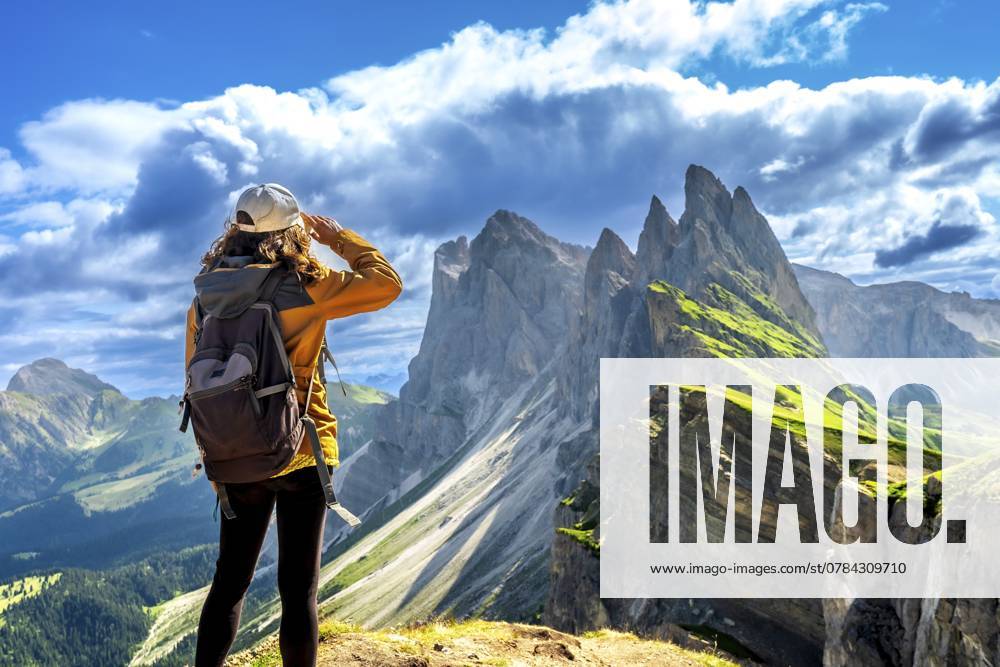 Wanderin, die ihre Augen abschirmt, während sie die atemberaubende Aussicht auf die Geislergruppe in den Dolomiten, Italien, an einem sonnigen Sommertag genießt, Europa Hiker shielding her eyes while enjoying the breathtaking view of the odle mountain range in the dolomites, italy, during a sunny summer day