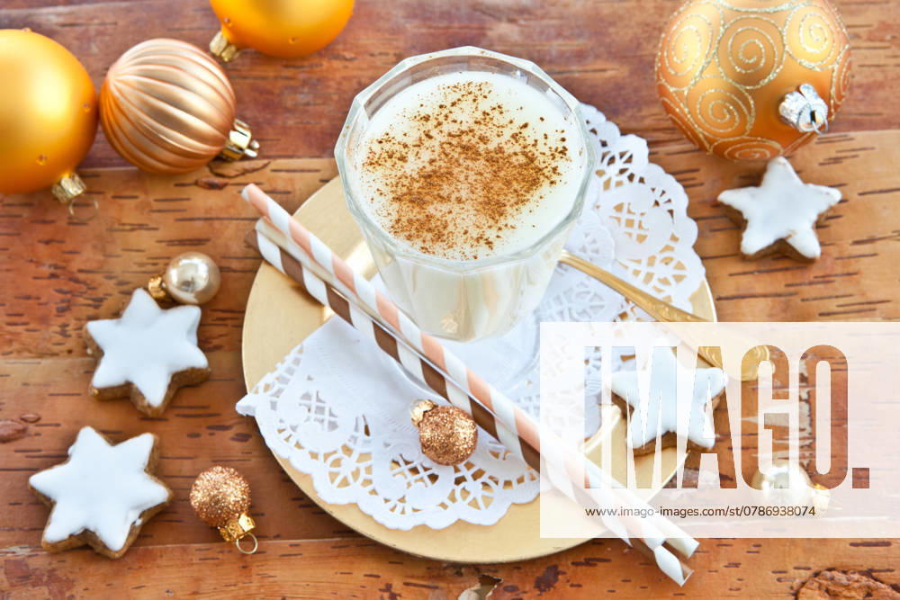 Ein Glas Eierpunsch mit Zimt und Weihnachtsdekoration