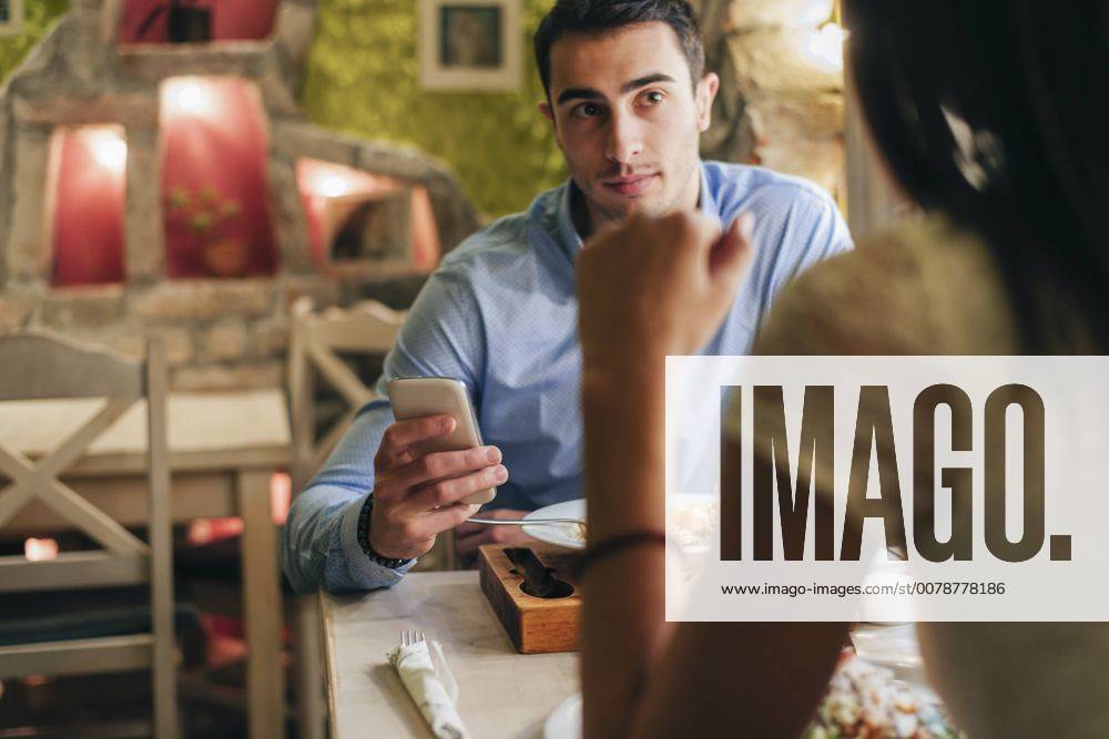 Man with cell phone face to face with his girlfriend in a restaurant model released Symbolfoto property released MOMF00108