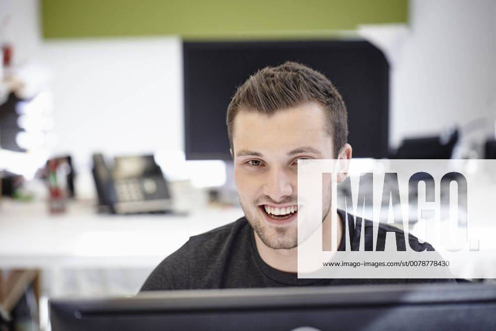 Young man working in office, looking at camera model released Symbolfoto property released RHF01904