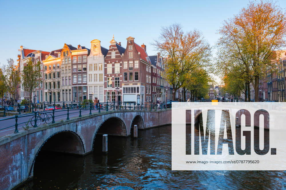 Herbstfarben, die sich bei einem sonnigen Abendspaziergang in den Grachten von Amsterdam spiegeln As the sun sets over Amsterdam, vibrant autumn leaves create a stunning palette along the canals of Amsterdam Keizersgracht