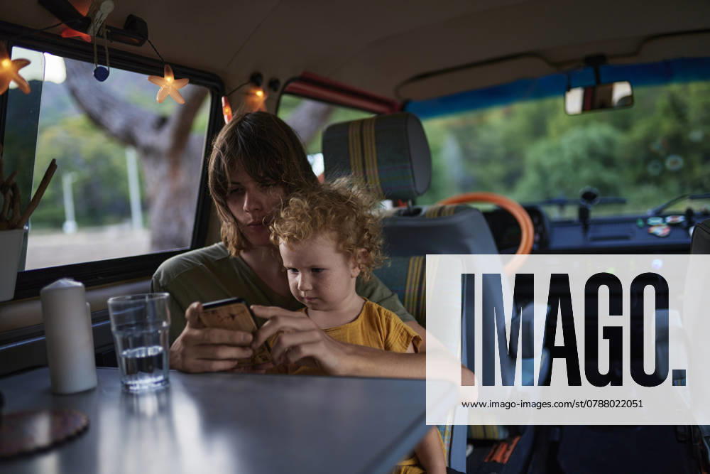 Girl playing on mobile phone sitting with brother in motor home model released, Symbolfoto property released, ANNF00747